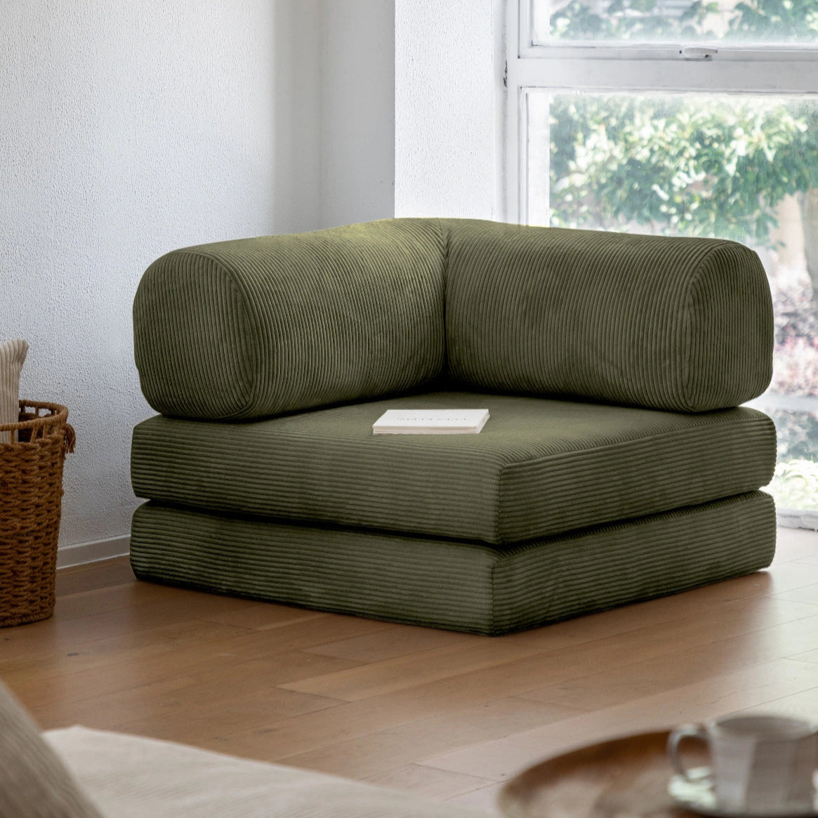 Green corner sofa in a living room with a window in the background